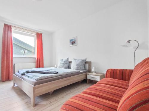 um quarto com uma cama e um sofá ao lado de uma janela em Haus Küstenperle em Cuxhaven