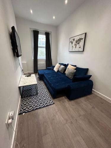 a living room with a blue couch and a television at Central locations 1 bed apartments sleeps 4 in London