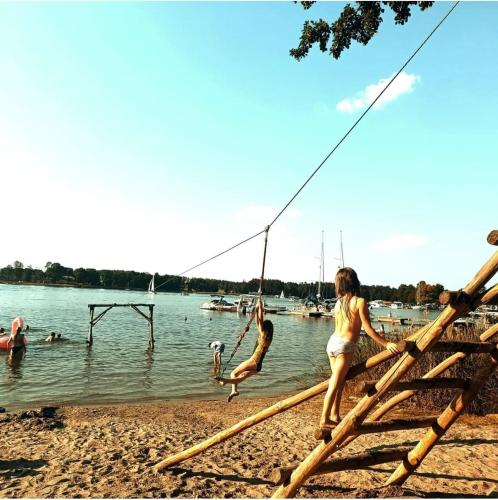a group of children playing on a woodenarf at a lake at Przystań Tło dla Mew in Rydzewo