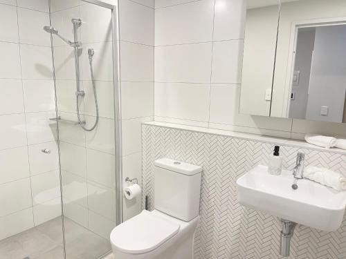 a bathroom with a toilet and a sink and a shower at Blackdiamond 504 - Beautiful, modern apartment - 2BdR, 2BthR in Tuggeranong