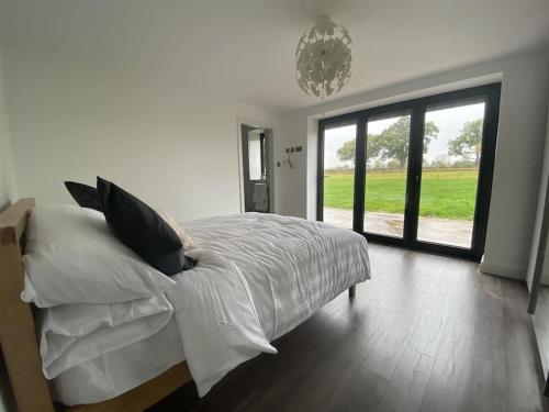 a bedroom with a bed with white sheets and a large window at PRIVATE LUXURY BARN IN ITS OWN 0.75ACRES in Sutton on the Hill