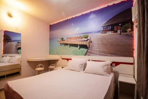 a bedroom with a large painting of a pier at Mirage Motel Guarulhos in São Paulo