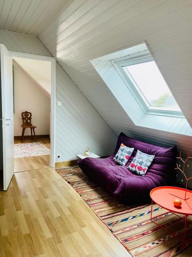 - un canapé violet dans le grenier avec une fenêtre dans l'établissement KerDesAmis - Tolles Ferienhaus in Strandnähe mit Sonnenterrasse, Boulebahn und großem Garten, à Pénestin