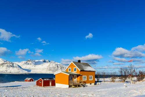 uma casa na neve com montanhas ao fundo em Lillevik Lofoten em Gimsøy