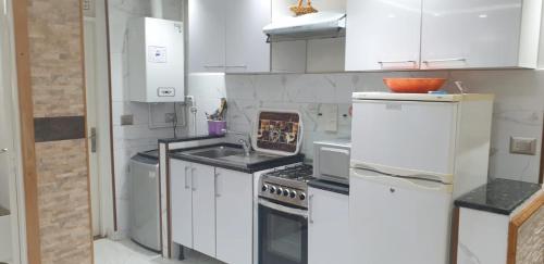 a white kitchen with a sink and a stove at Didon Manar in Tunis