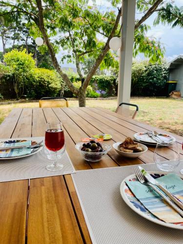 - une table en bois avec des assiettes de nourriture et un verre de vin dans l'établissement KerDesAmis - Tolles Ferienhaus in Strandnähe mit Sonnenterrasse, Boulebahn und großem Garten, à Pénestin