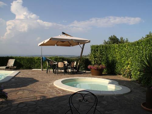 a patio with an umbrella and a table and chairs at DA ROSA B&B in Neviglie