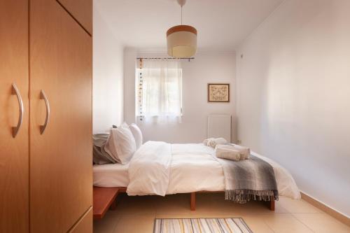 a bedroom with a bed with white sheets and a window at Spartan Gem Apartment in Sparti