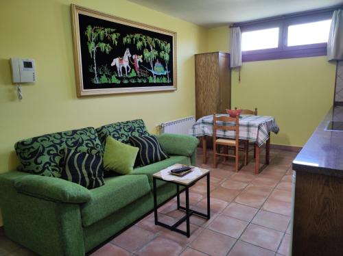a living room with a green couch and a table at Apartamento Rural in Cangas de Onís