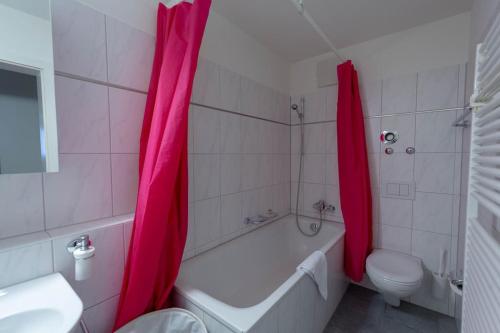 a bathroom with a tub and a toilet and pink shower curtain at Executive 2 bedroom flat / city center (Hösch 5) in Zürich