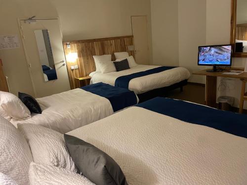 a hotel room with three beds and a flat screen tv at Logis Hôtel de France & Restaurant Pamiers in Pamiers
