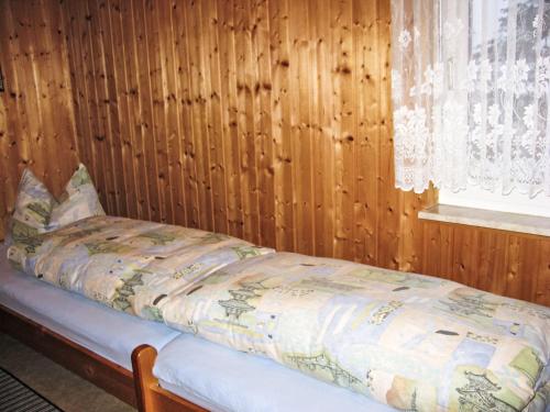 a bed in a room with a wooden wall at Holiday Home Aurora-2 by Interhome in Kurort Steinbach-Hallenberg