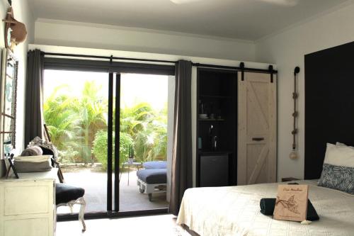 - une chambre avec un lit et une porte coulissante en verre dans l'établissement Casa Mantana Bonaire, à Kralendijk