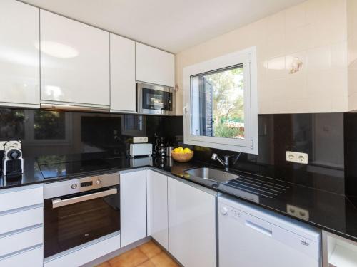 Una cocina con gabinetes blancos y encimeras negras. en Apartment Faner by Interhome, en Llançà