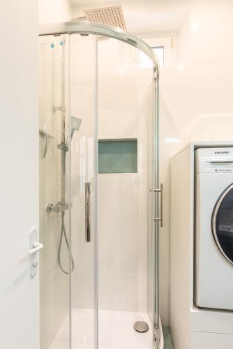 une douche avec une porte en verre à côté d'un lave-linge dans l'établissement Charming flat - 4 guests - Saint-Germain des pres, à Paris