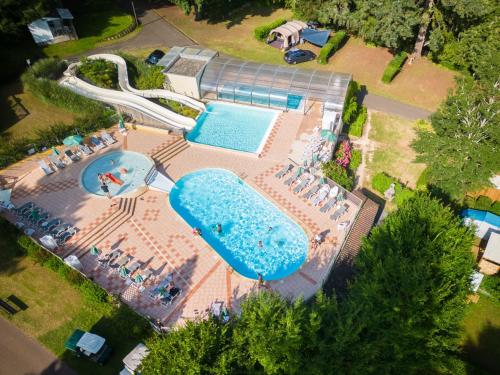 een uitzicht over een zwembad met tafels en stoelen bij Holiday Home Camping Sunélia Le Séquoia-3 by Interhome in Payrac