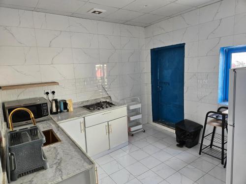 a kitchen with white cabinets and a blue door at منزل حجري بحديقتين in Hajlah