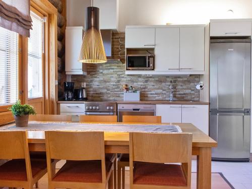 a kitchen with white cabinets and a wooden table with chairs at Holiday Home Nilikuru g18 by Interhome in Saariselka