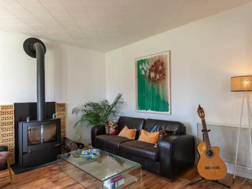 - un salon avec un canapé en cuir et une guitare dans l'établissement Holiday Home Chez Eric by Interhome, à Névez