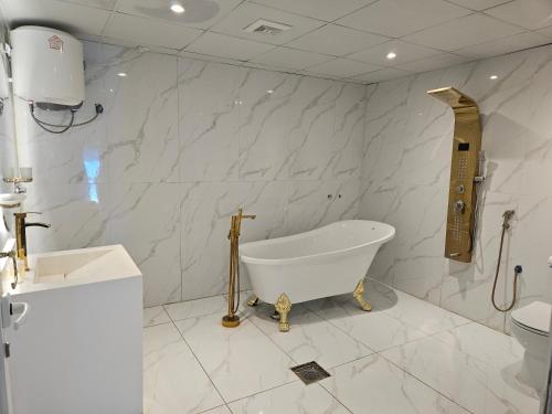 uma casa de banho branca com uma banheira e um WC em منزل حجري بحديقتين em Hajlah