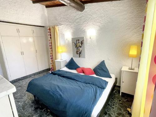 une chambre avec un lit avec des draps bleus et des oreillers rouges dans l'établissement Villa charmante à Porto-Vecchio avec vue sur la montagne., à Porto-Vecchio