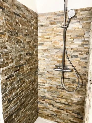 La salle de bains est pourvue d'une douche et d'un mur en briques. dans l'établissement Villa charmante à Porto-Vecchio avec vue sur la montagne., à Porto-Vecchio