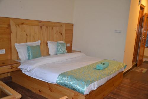 een slaapkamer met een groot bed met een houten hoofdeinde bij hotel sparkling in Manāli