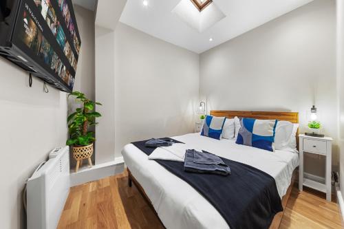a bedroom with a large bed with blue pillows at Boho 1-BR Peakham Rye Lane in London