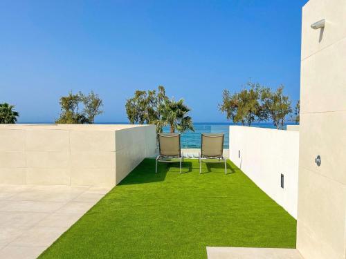 an outdoor patio with two chairs and grass at Holiday Home Ocean Front-Cordial Santa Águeda by Interhome in Arguineguín
