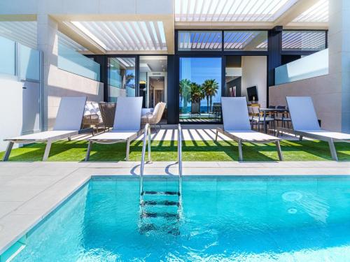 a swimming pool with chairs and a house at Holiday Home Ocean Front-Cordial Santa Águeda by Interhome in Arguineguín