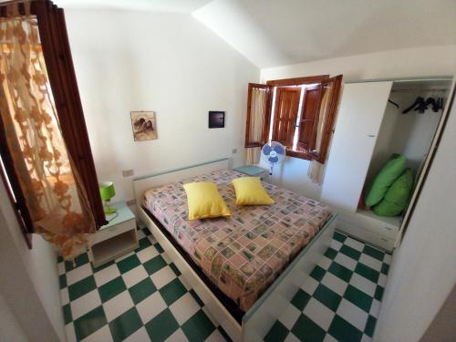 a small bedroom with a bed with two yellow pillows at Casa Maci in Torre Dei Corsari