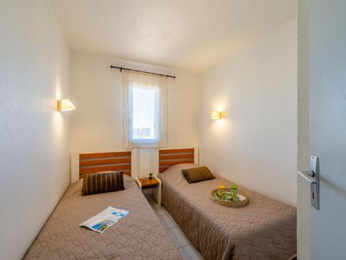 une petite chambre avec deux lits et une fenêtre dans l'établissement Apartment Primavera-3 by Interhome, au Cap d'Agde
