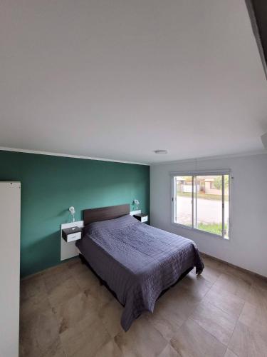 a bedroom with a bed and a green wall at Punto Mar in Balneario Claromecó