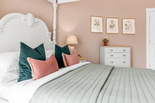 a bedroom with a white bed with green and pink pillows at Must see - Georgian Mansion I Suffolk Retreat in Beccles