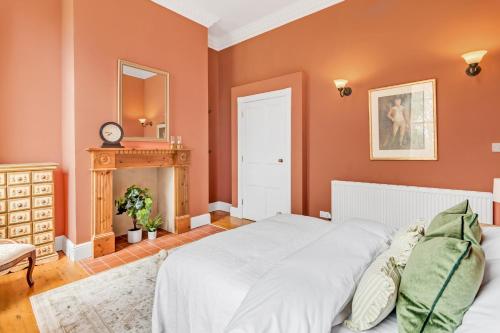 a bedroom with orange walls and a bed and a fireplace at Must see - Georgian Mansion I Suffolk Retreat in Beccles