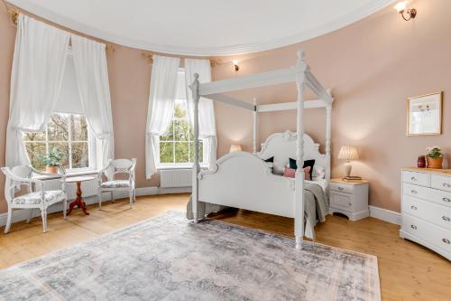 a bedroom with a white canopy bed and a desk at Must see - Georgian Mansion I Suffolk Retreat in Beccles