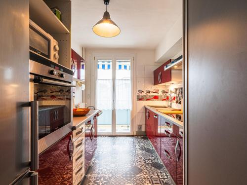 une cuisine avec des armoires rouges et une grande fenêtre dans l'établissement Apartment Les Platanes by Interhome, à Narbonne