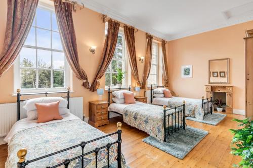 two beds in a room with windows at Stunning Historic Suffolk Mansion in Beccles