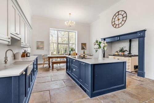 a large kitchen with blue cabinets and a table at Must see - Georgian Mansion I Suffolk Retreat in Beccles