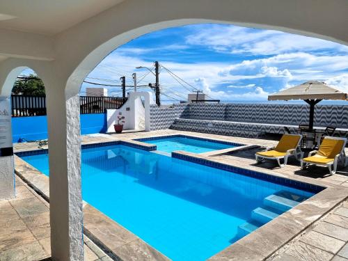 a swimming pool with two chairs and an umbrella at Santorini Praia Hotel in Natal