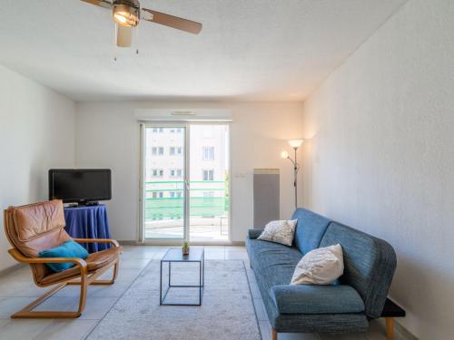 un salon avec un canapé bleu et une chaise dans l'établissement Apartment Les Capucines by Interhome, à Narbonne