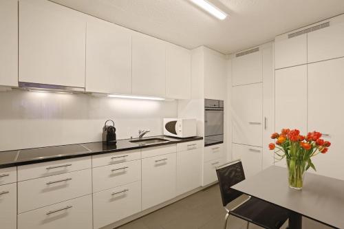 a white kitchen with a table and a vase of flowers at Fantastic 2 bedroom flat close to the lake (Mainau 4) in Zürich
