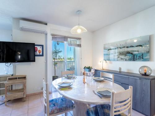 une salle à manger avec une table et une télévision dans l'établissement Apartment Le Berlioz by Interhome, au Pradet