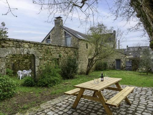 a wooden picnic table in front of a stone house at Holiday Home Maison Ty Mad by Interhome in Belz