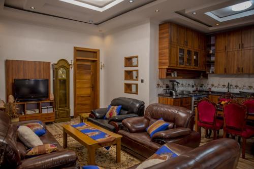 sala de estar con muebles de cuero y cocina en Simaza Villa, en Kigali