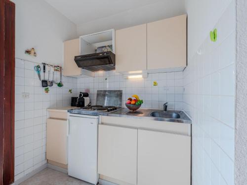 une petite cuisine avec des armoires blanches et un évier dans l'établissement Apartment Les Portes de la Mer-2 by Interhome, à Saint-Cyprien