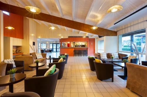 a restaurant with couches and tables and chairs at SOWELL HÔTELS Les Jardins du Cap in Cap d'Agde