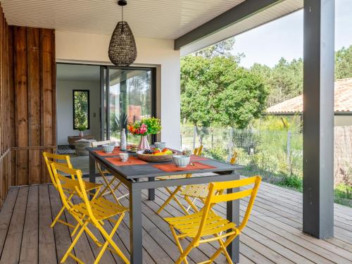 a patio with a wooden table and yellow chairs at Holiday Home Hotel du Nord by Interhome in Mimizan