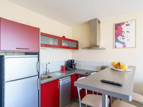 une cuisine avec des armoires rouges et un réfrigérateur blanc dans l'établissement Apartment Impératrice-2 by Interhome, à Biarritz