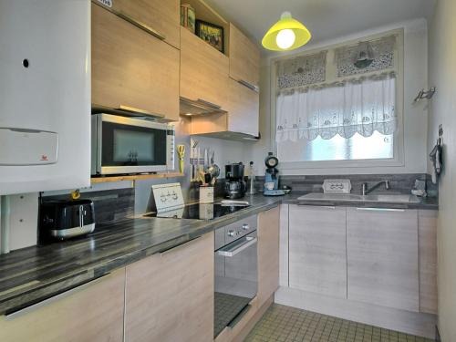 La cuisine est équipée de placards en bois, d'un évier et d'un four micro-ondes. dans l'établissement Apartment Arvor Ambiance by Interhome, à Vannes